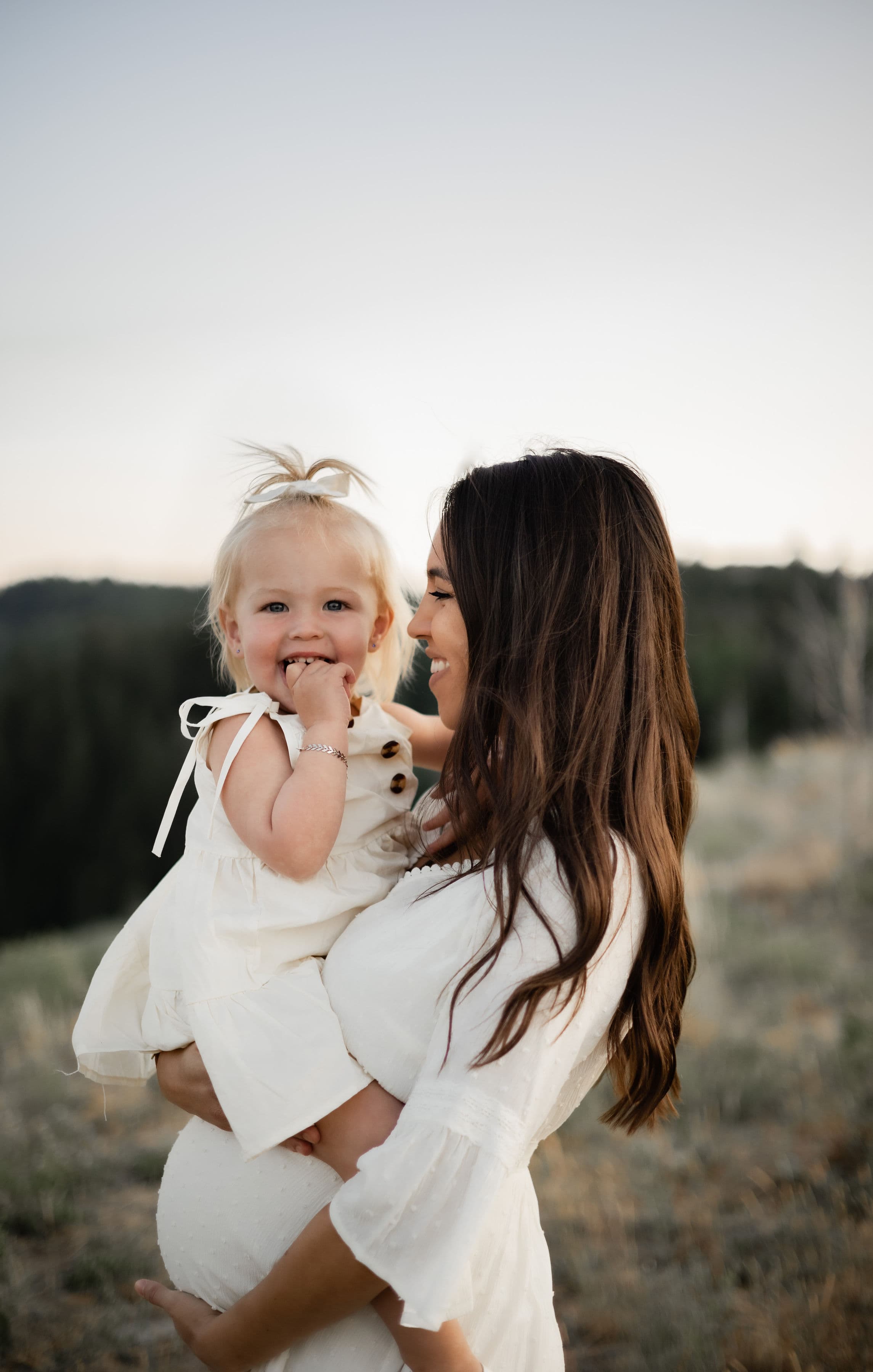 Nicole holding her daughter in a sunlit field at golden hour